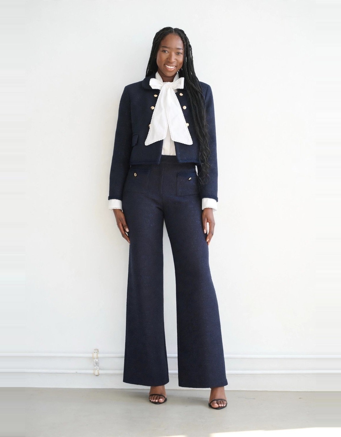 The same photo, wearing the tailored look: bouclé jacket, blouse with tie bow and wide leg trousers. AI generated.
